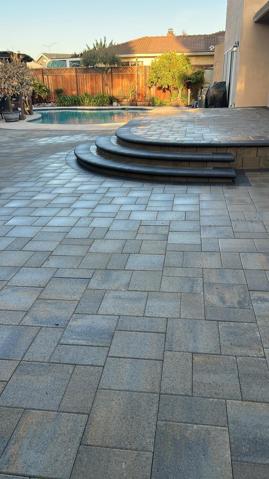 Gray paver pool deck with curved raised steps and bullnose caps