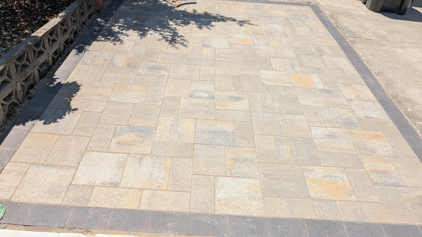 Wide paver parking pad with dark border finished in a random pattern