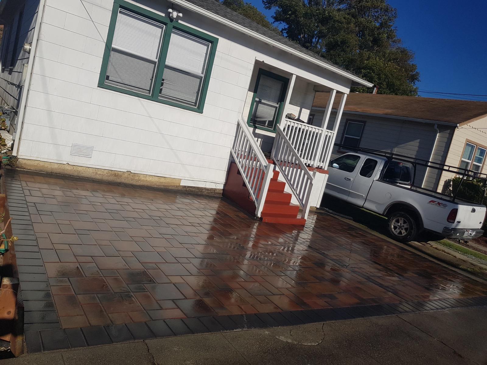 Multi-tone paver driveway with charcoal border beside a home's front steps
