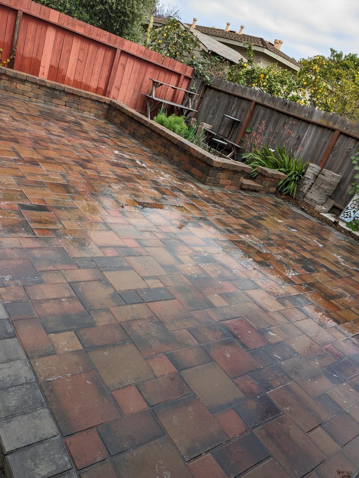 Multi-tone paver patio with raised block planter beds along a redwood fence