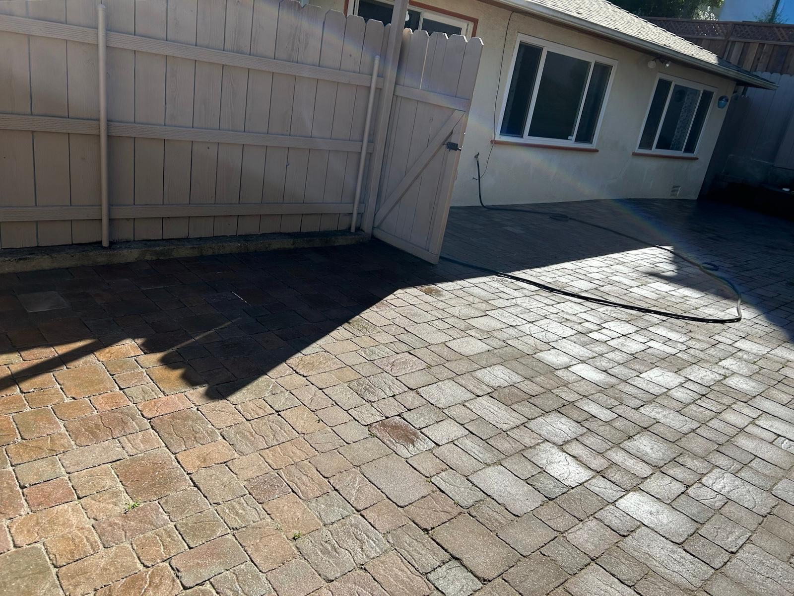 Shaded multi-tone paver patio next to a light wood privacy fence