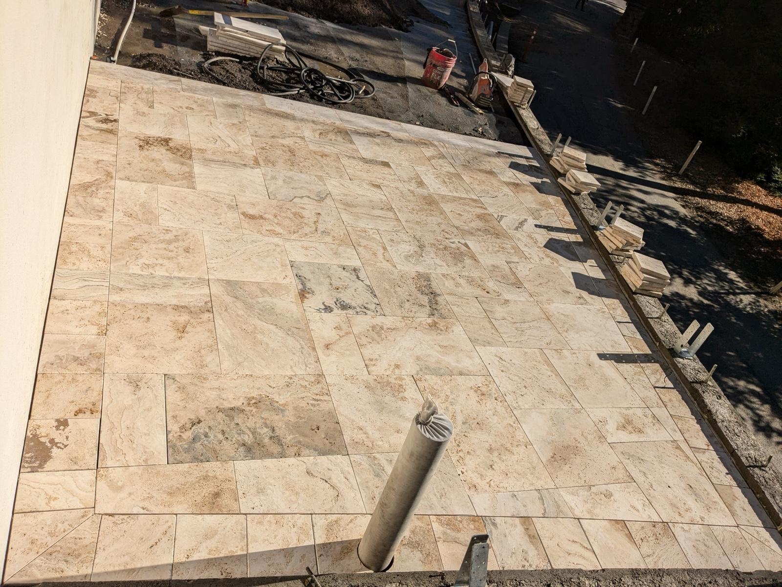 Completed backyard hardscape with paver patio, seating wall, and decorative plantings